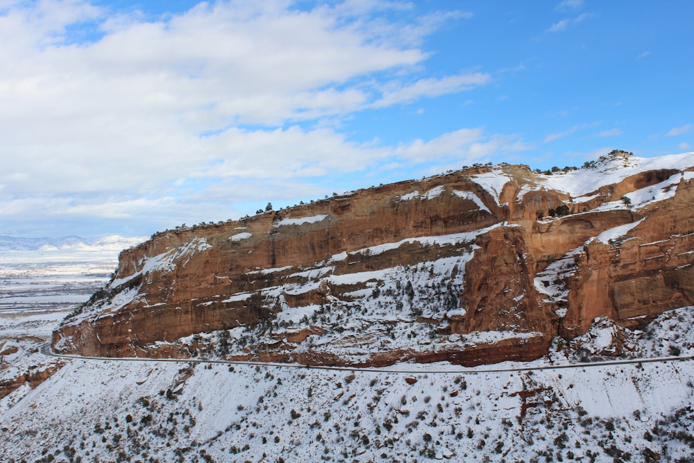 rocky hill covered with snow under blue and white skies