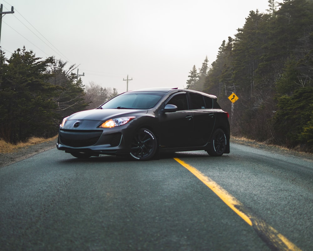 black Mazda 5-door hatchback in middle of road