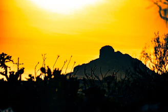 Minimalist desert mountain silhouette in muted gold against a near-black textured backdrop, symbolizing resilience and growth.