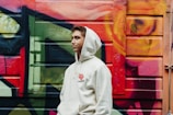 A model showcasing a trendy hoodie against a graffiti wall.