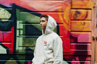 Close-up of a confident teen girl wearing a bright red hoodie with the ChaseVibe logo, smiling against a colorful graffiti wall.