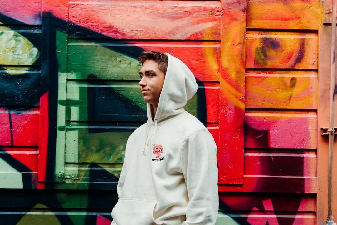 man wearing hoodie in front of mural