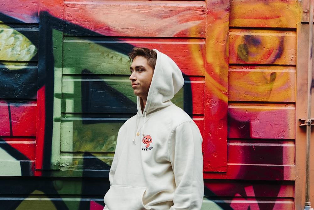 man wearing hoodie in front of mural