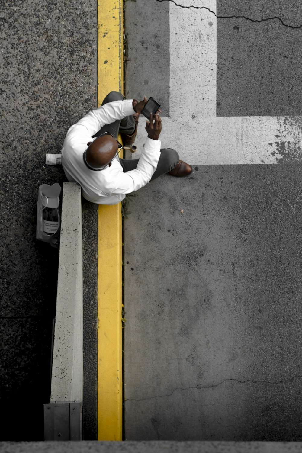 man sits on yellow painted gutter