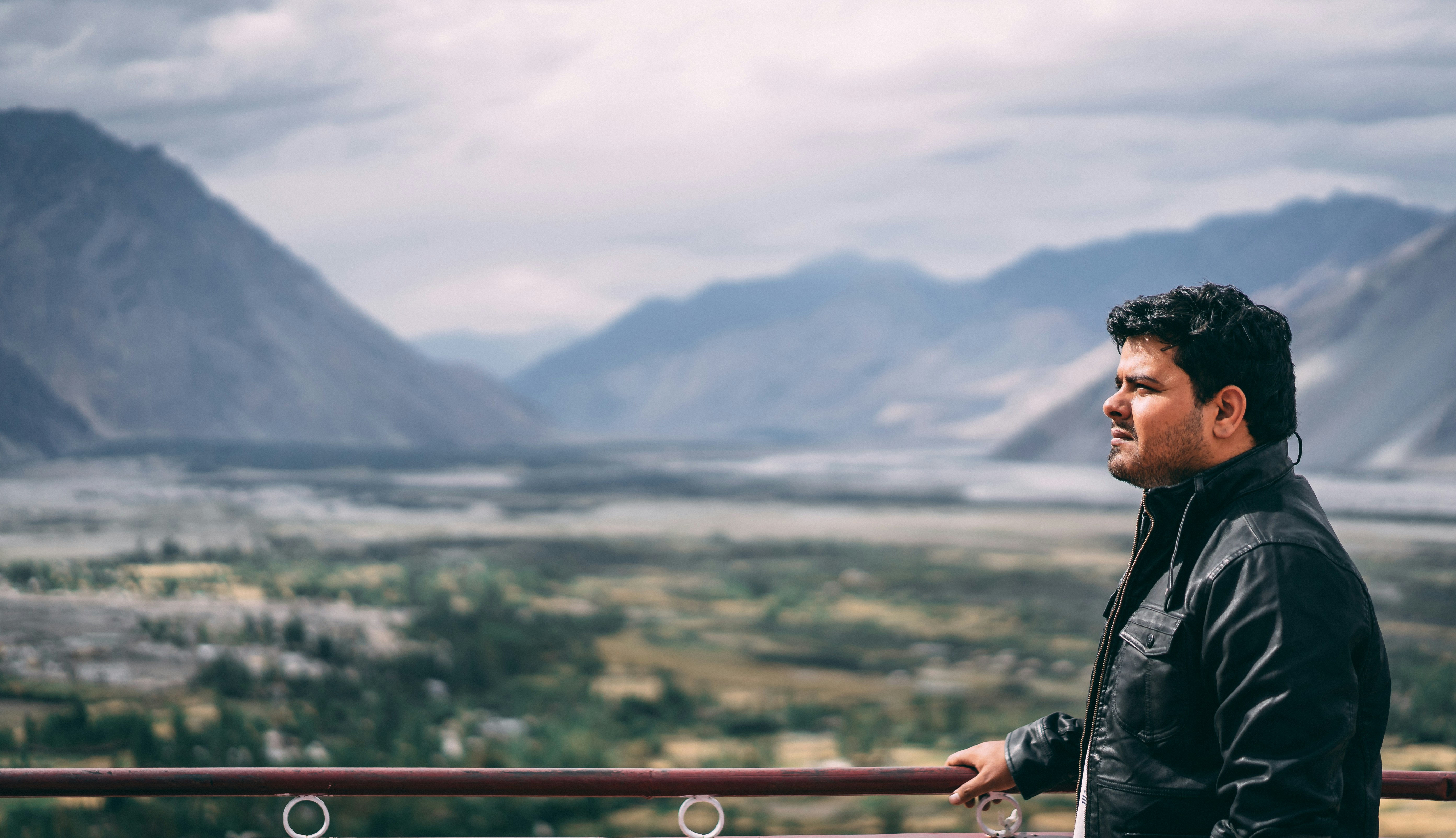 a man standing on top of a balcony next to mountains