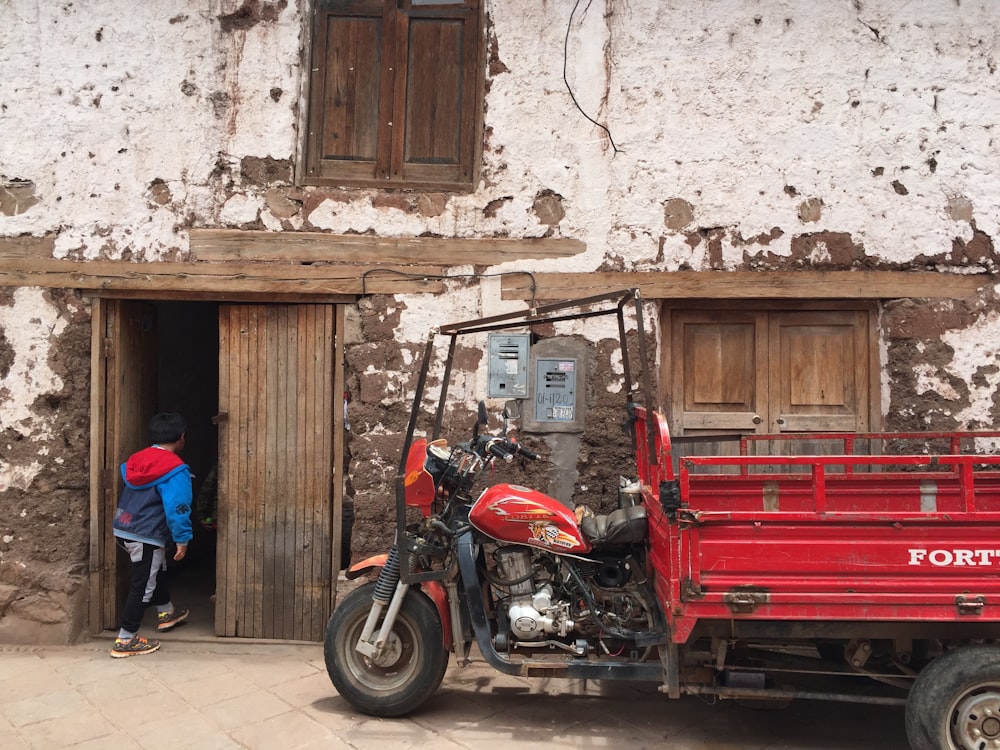 moto rouge et noire près de la maison et personne sur le point d’entrer dans la maison