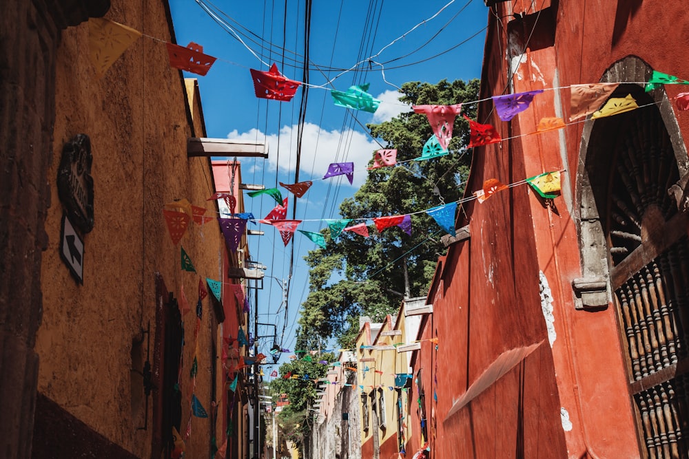 assorted-color pennant flags in between concrete buildings