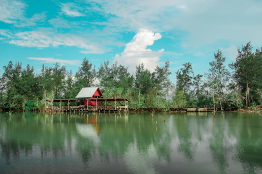 a red house sitting on top of a lake next to a forest