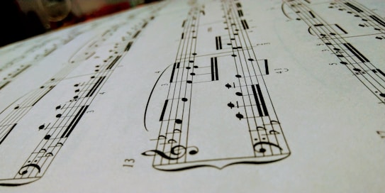 A close-up view of a sheet of musical notation featuring various notes, clefs, and musical symbols laid out on a staff. The image focuses on the details of the music manuscript with emphasis on the notes and lines.