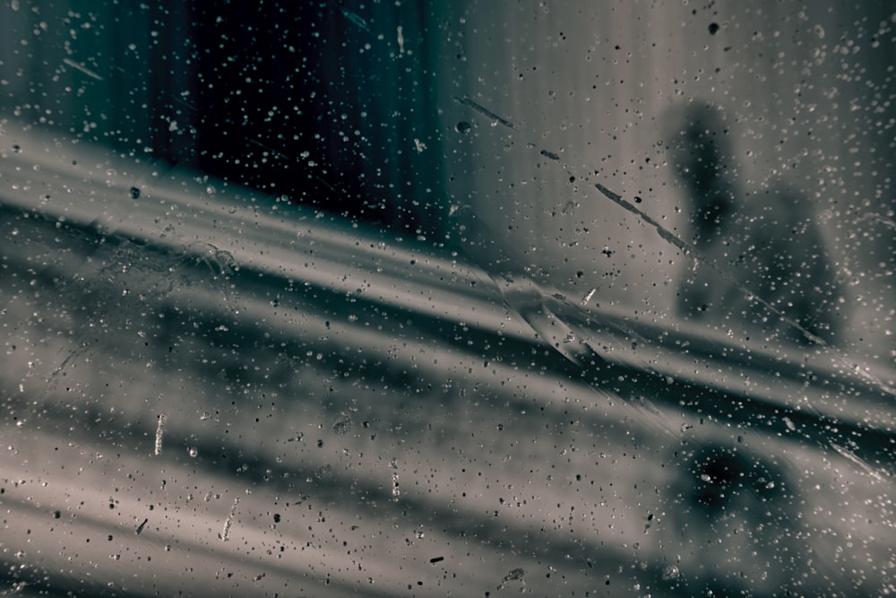 una finestra con gocce di pioggia su di esso e una persona sullo sfondo