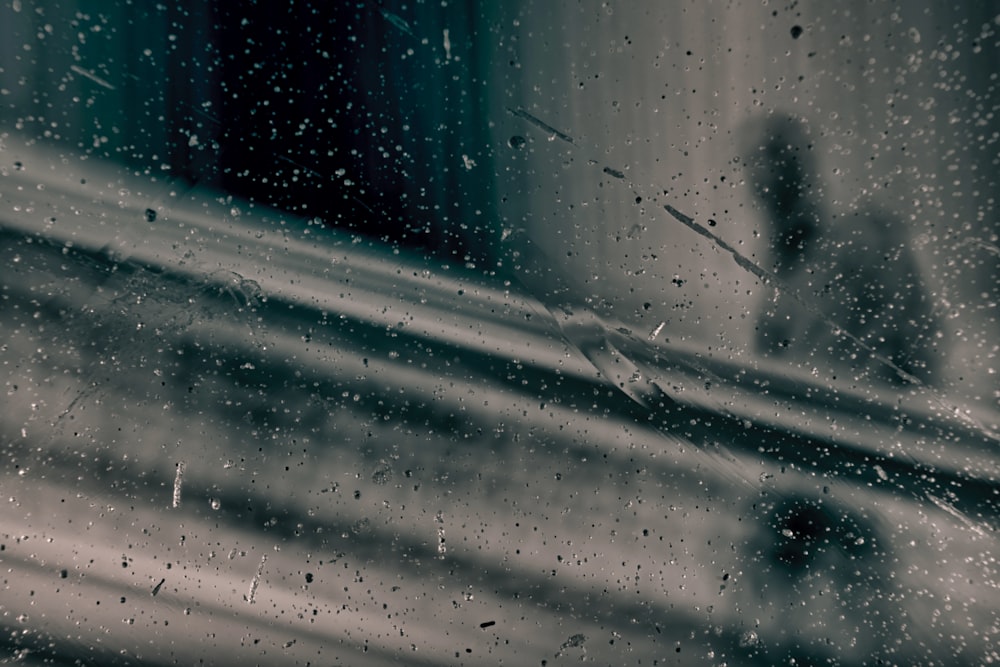 a window with rain drops on it and a person in the background