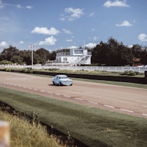 A close-up of a vintage legends car racing on a Finnish track under clear skies.