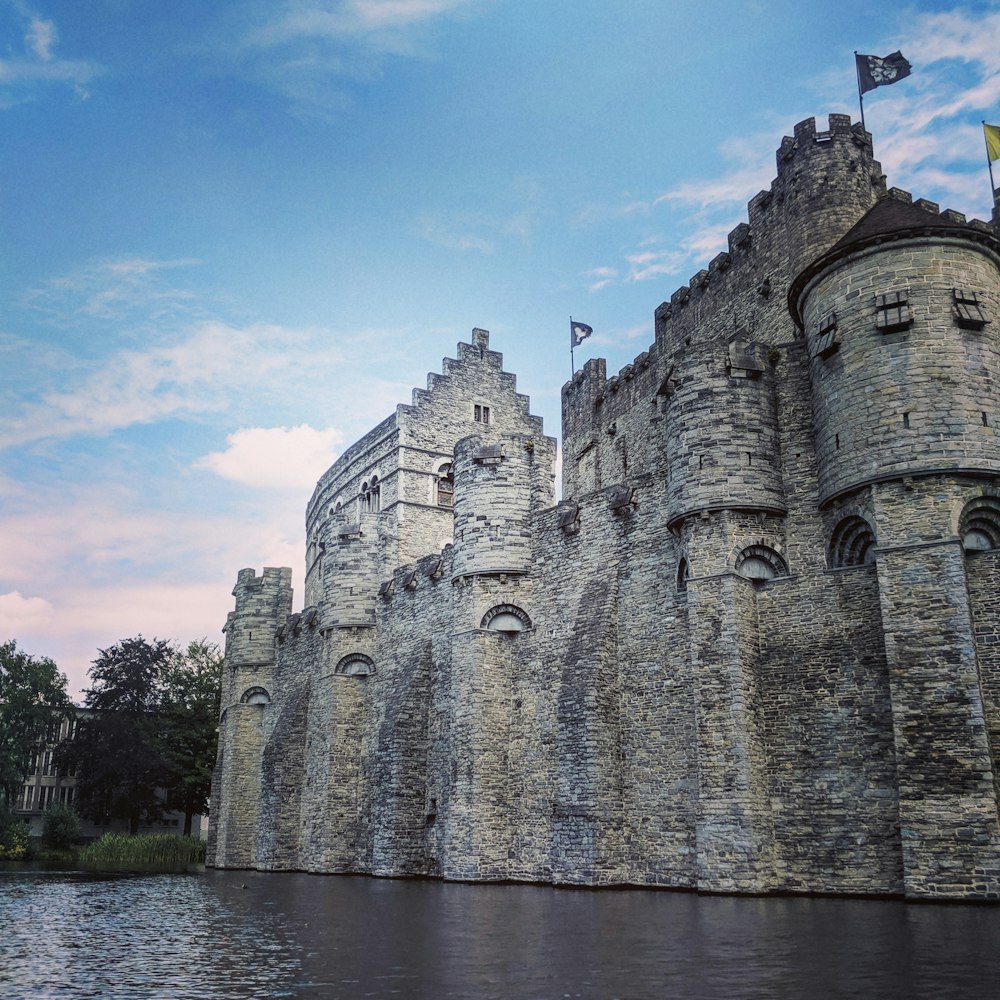 um grande castelo como estrutura sentada ao lado de um corpo de água