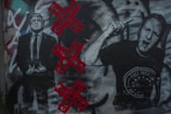Graffiti artwork featuring two figures, one in a suit and the other with an expressive hand gesture. The background includes red Xs with the word 'CORRUPT' in black. Various colors and textures are visible, adding depth and complexity.