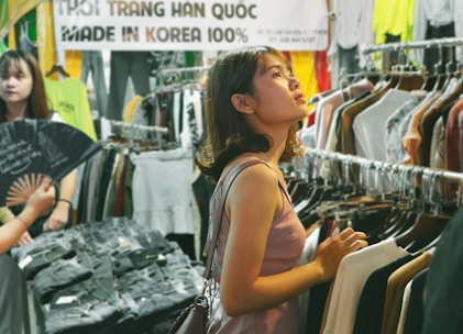 A stylish shopper selecting trendy clothes in a vibrant Seoul boutique.