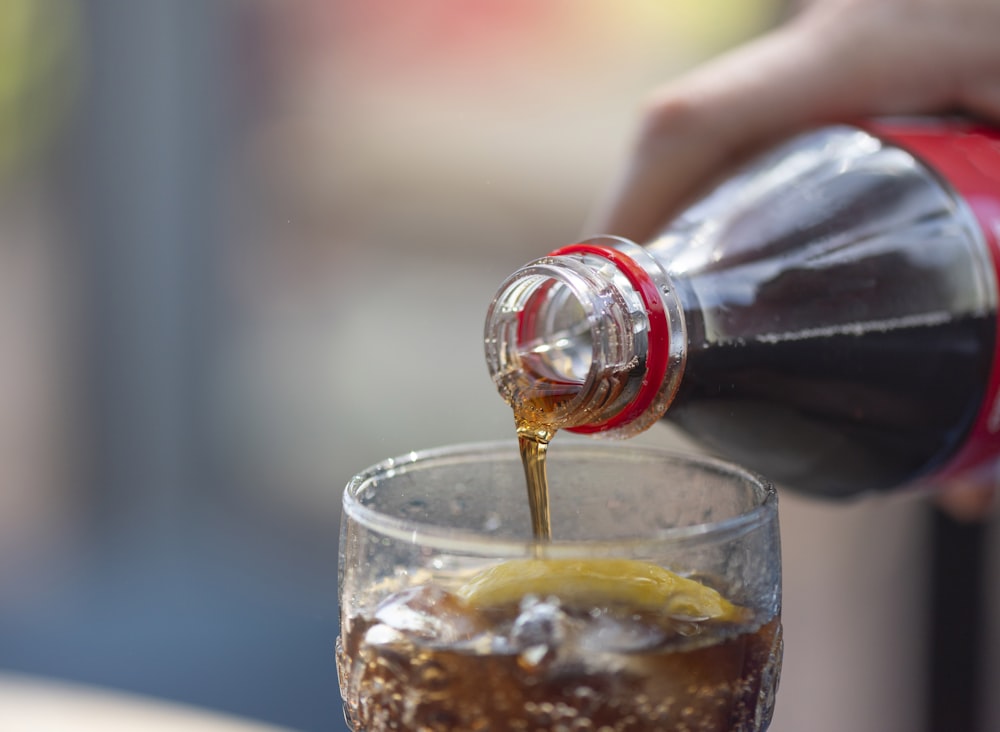 person pouring soda on glass