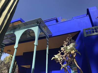Exterior of a bungalow in Bengaluru with vibrant blue and cream paint, highlighting detailed texture work.