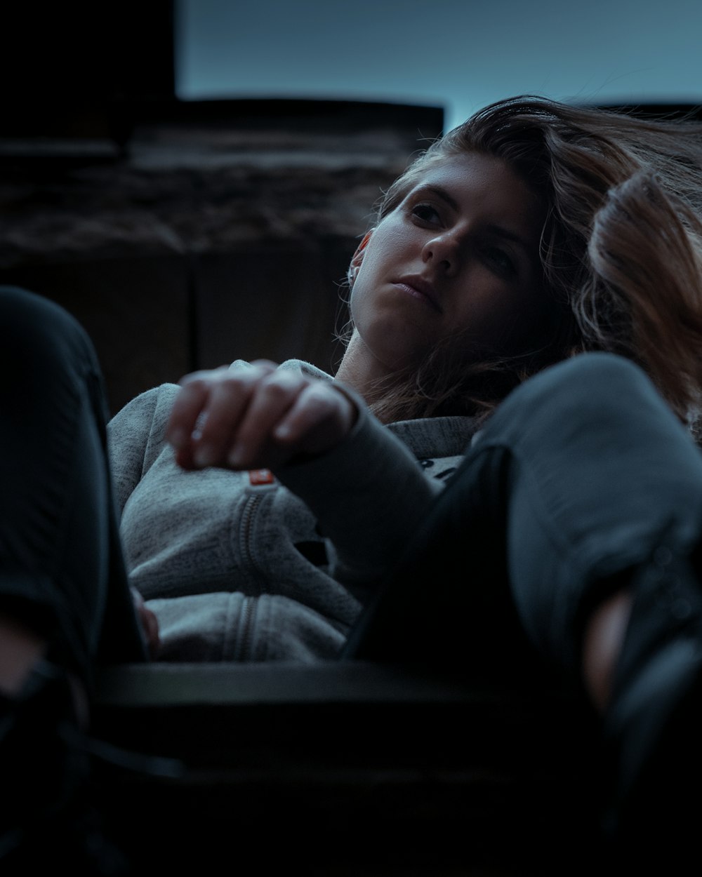 a woman sitting on a couch with her hair blowing in the wind