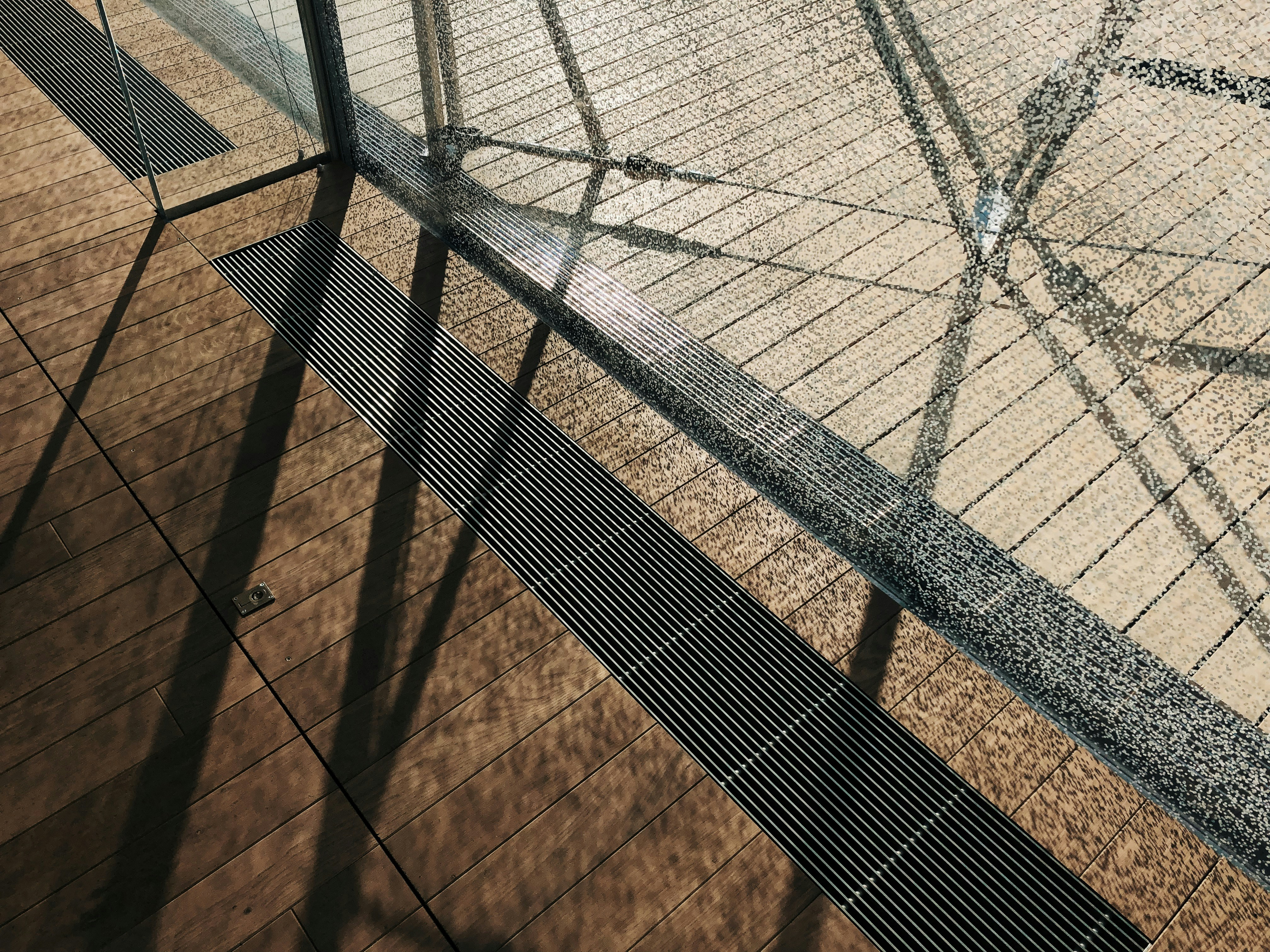 Modern aluminum patio cover with exposed beams over a wooden deck, afternoon sunlight filtering through