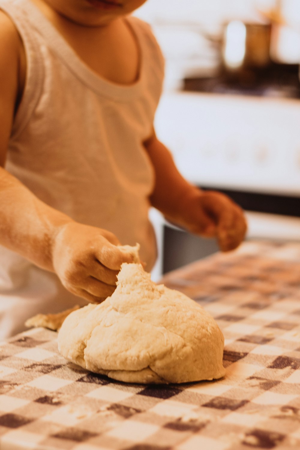 boy in white tank top playing with dough