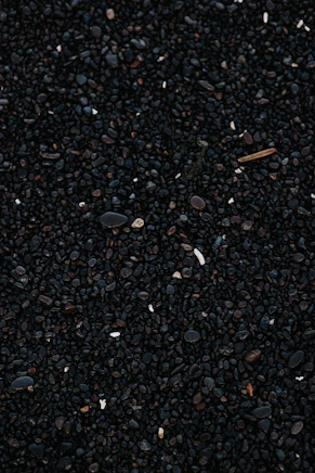 a close up of a cell phone laying on top of a pile of gravel