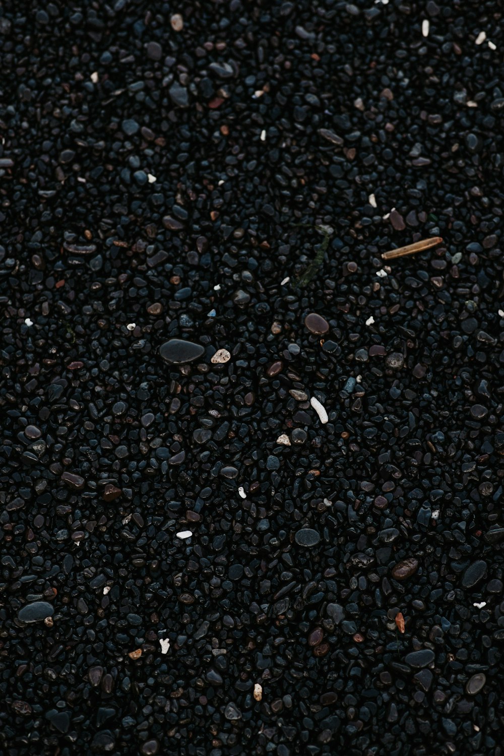 a close up of a cell phone laying on top of a pile of gravel