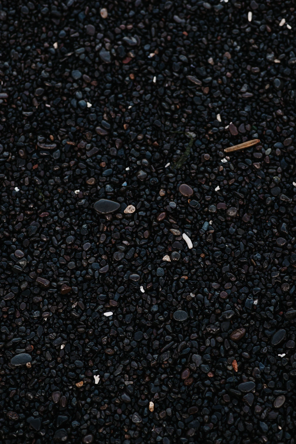 Close-up view of black gravel surface with scattered small rocks and varying stone sizes