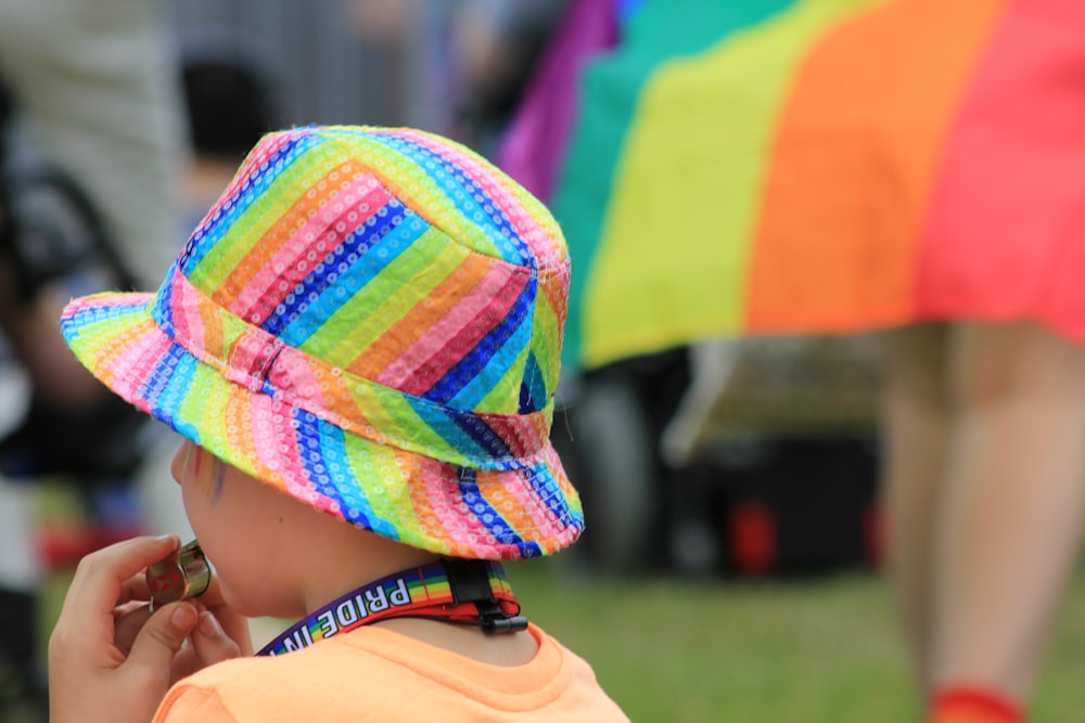 a small child wearing a colorful hat while talking on a cell phone