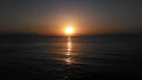 Sunset casting warm orange hues over a calm ocean horizon.