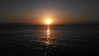 A warm sunset over a calm ocean, with a silhouette of a traveler gazing at the horizon.