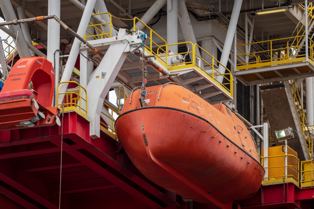 a large orange boat being lifted by a crane