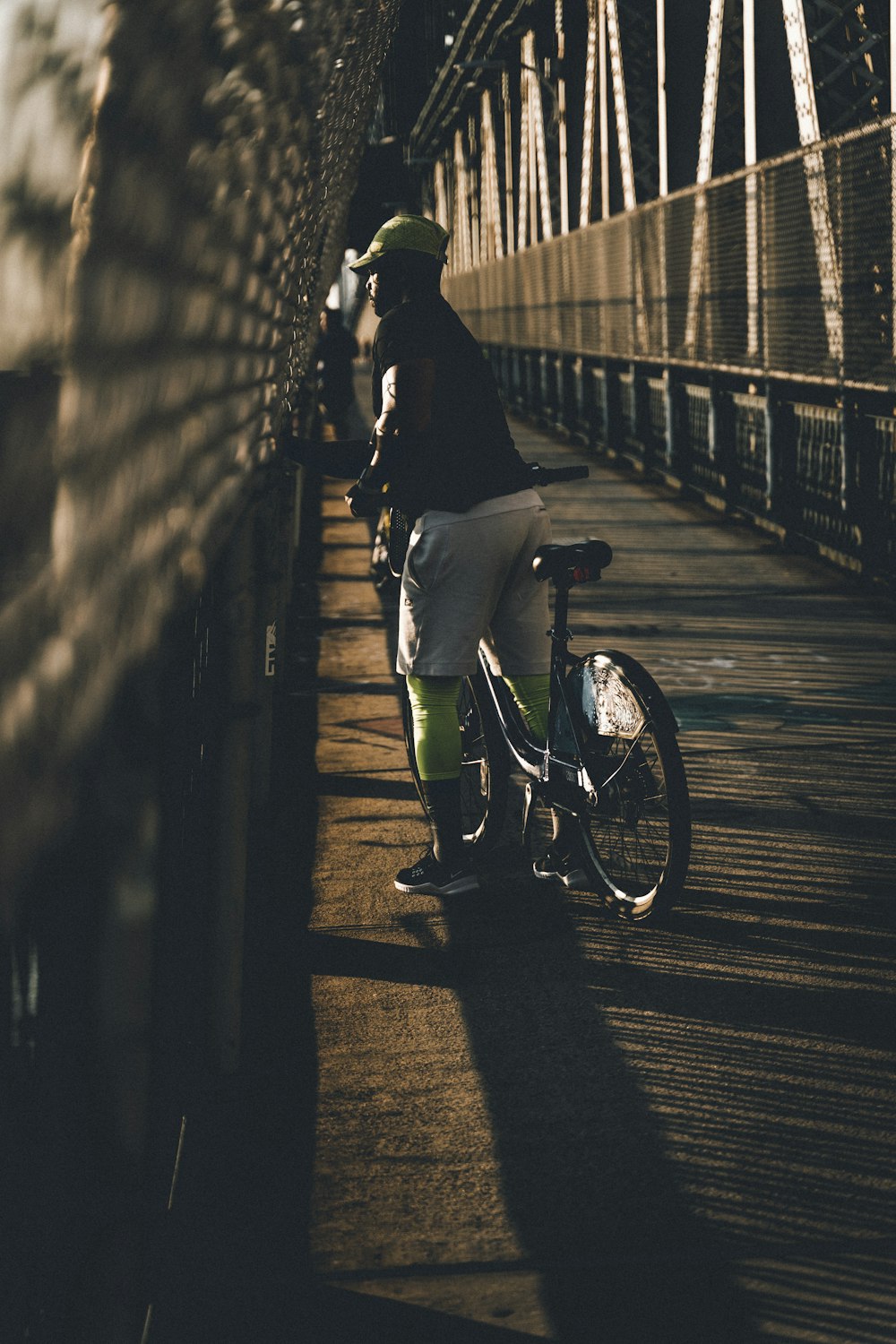 a person standing next to a bike on a bridge