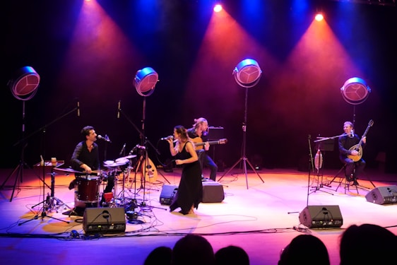 The four members of Nora’s Inspiration performing energetically on a warmly lit stage.