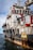 A large rescue ship on the water is visible, featuring a robust structure with multiple decks and safety equipment on board. The hull is painted with a combination of white and dark colors, and there are several large tires attached to the side, presumably for protection or docking purposes. Red pipes and lifebuoys are mounted on the exterior, and the words 'RESCUE' and 'SAFETY FIRST' are prominently displayed. The ship is equipped with cranes and other machinery, indicating its readiness for emergency situations.
