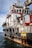 A large rescue ship on the water is visible, featuring a robust structure with multiple decks and safety equipment on board. The hull is painted with a combination of white and dark colors, and there are several large tires attached to the side, presumably for protection or docking purposes. Red pipes and lifebuoys are mounted on the exterior, and the words 'RESCUE' and 'SAFETY FIRST' are prominently displayed. The ship is equipped with cranes and other machinery, indicating its readiness for emergency situations.