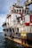 A large rescue ship on the water is visible, featuring a robust structure with multiple decks and safety equipment on board. The hull is painted with a combination of white and dark colors, and there are several large tires attached to the side, presumably for protection or docking purposes. Red pipes and lifebuoys are mounted on the exterior, and the words 'RESCUE' and 'SAFETY FIRST' are prominently displayed. The ship is equipped with cranes and other machinery, indicating its readiness for emergency situations.