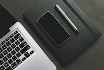 A close-up of a traffic ticket with a pen and a laptop in the background.