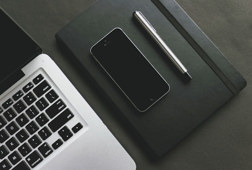 A close-up of a smartphone and a laptop on a desk.
