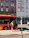 A smiling passenger boarding a clean red bus at a sunny station.