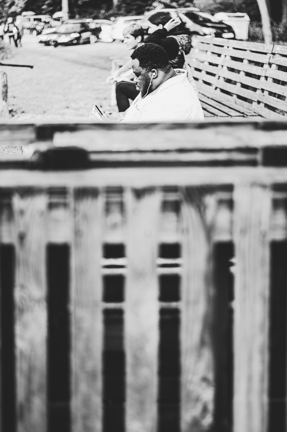 grayscale photo of man sitting on wooden bench