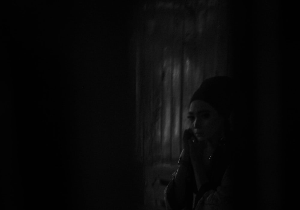 a woman standing in a dark room talking on a cell phone