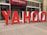 Large red and white letters spelling out 'YAHOO' are positioned outside a building labeled 'Global Business Centre.' The letters are three-dimensional and stand on the sidewalk, creating a striking visual against the building's facade.