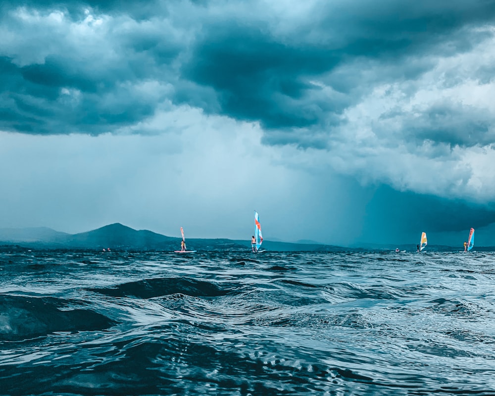 um grupo de veleiros no oceano sob um céu nublado