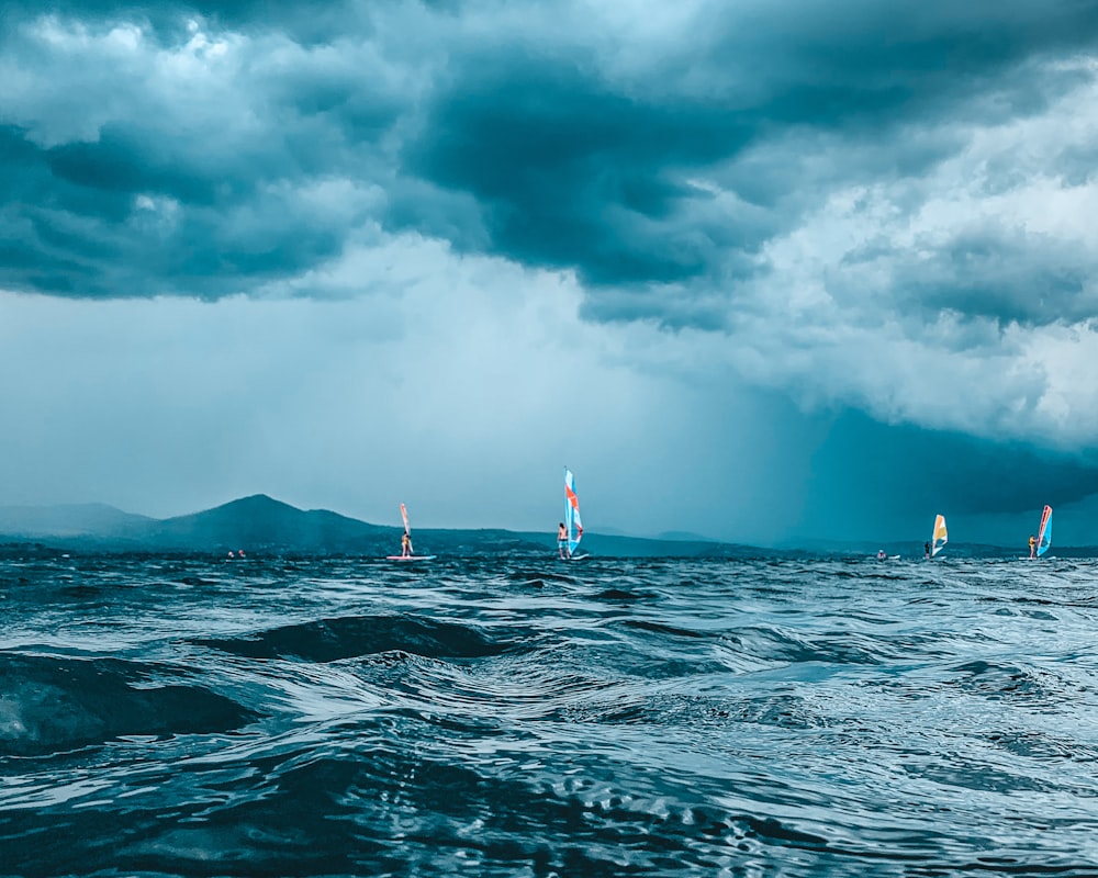 Eine Gruppe von Segelbooten im Ozean unter einem bewölkten Himmel