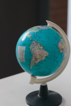 A globe displaying parts of North and South America is mounted on a stand. It is positioned on a light surface, with a focus on the Americas and some visible labels for countries like Brazil.