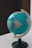 A globe displaying parts of North and South America is mounted on a stand. It is positioned on a light surface, with a focus on the Americas and some visible labels for countries like Brazil.