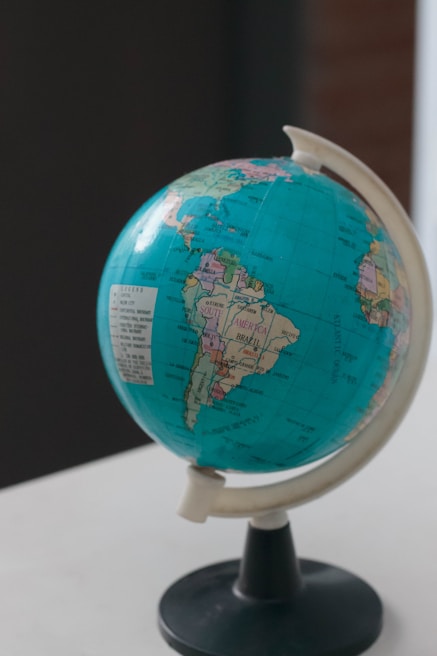 A globe displaying parts of North and South America is mounted on a stand. It is positioned on a light surface, with a focus on the Americas and some visible labels for countries like Brazil.