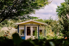 white and blue house surrounded by green trees