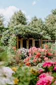 building covered with green plants and surrounded by petaled flowers