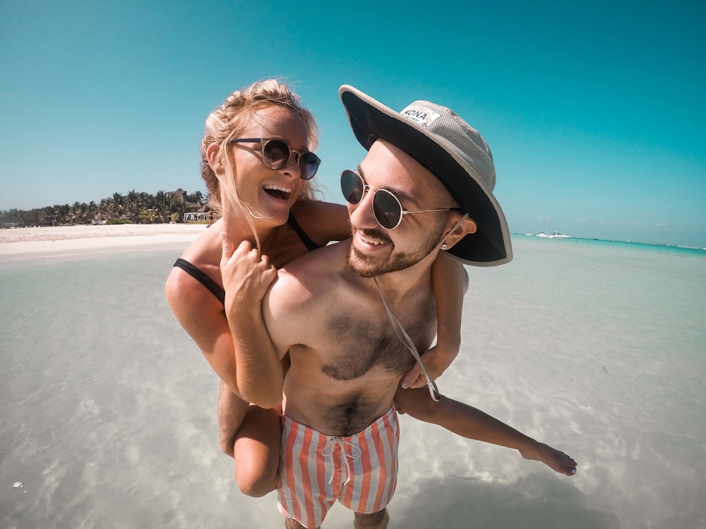 a man carrying a woman on his back on the beach